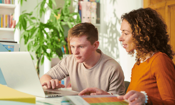 Male student at home on the laptop working with female instructor