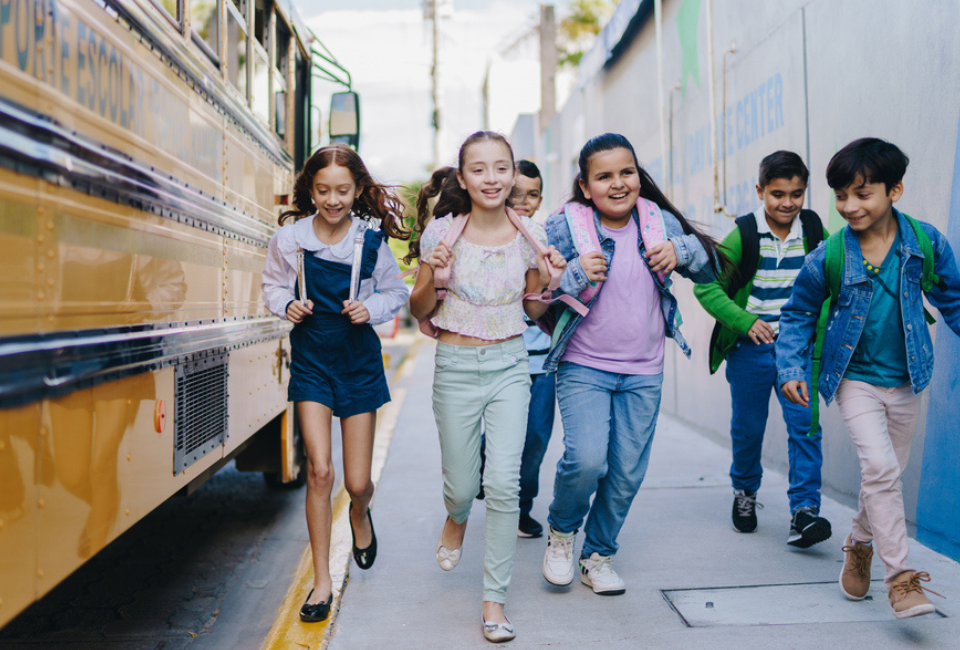 Excited children run off the bus to enter school for the first day of back to school.